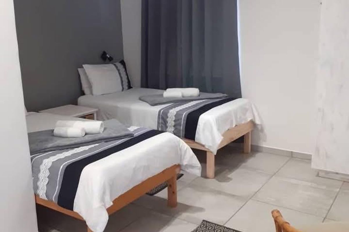 A bedroom featuring tiled flooring and a neutral color scheme with a grey accent wall.