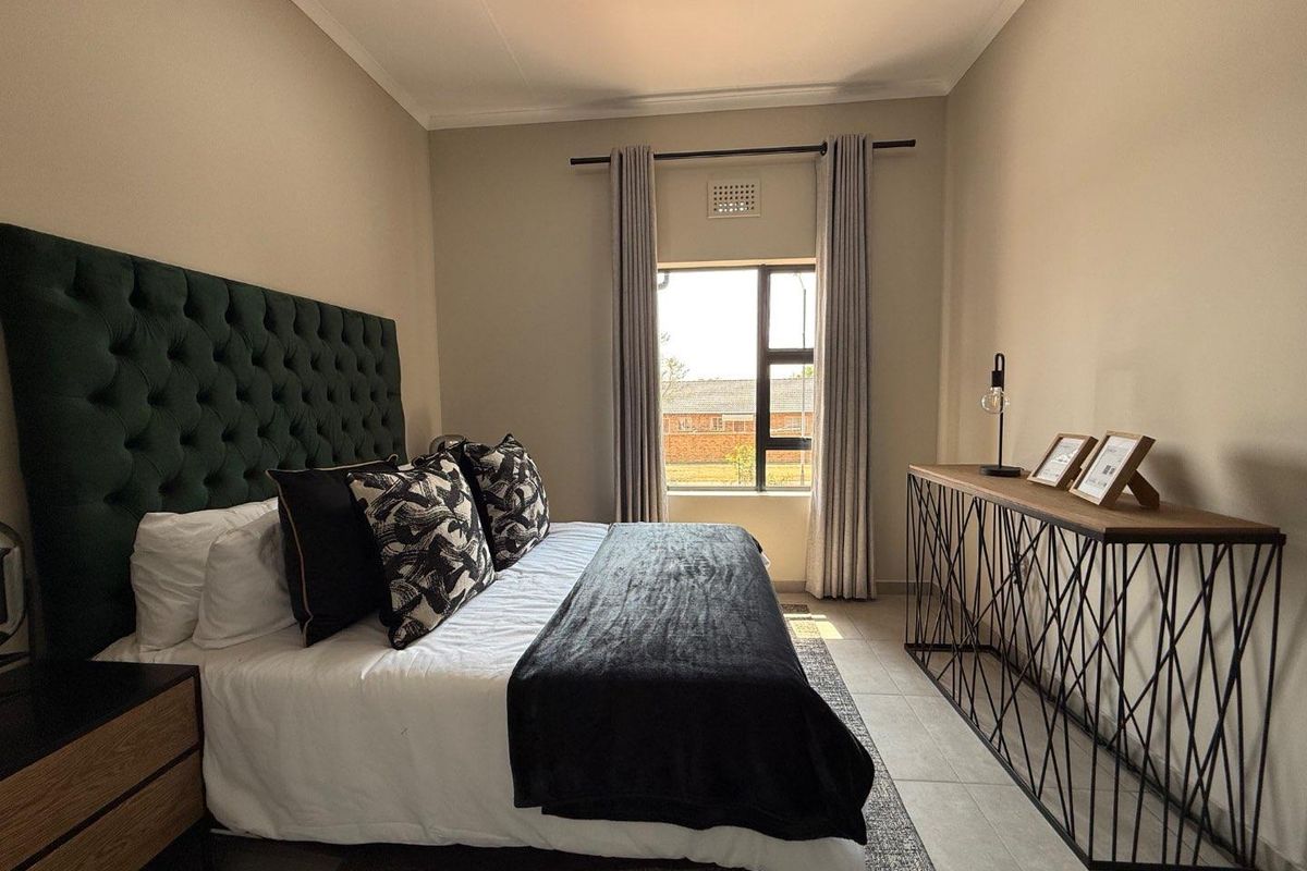 A well-maintained bedroom featuring neutral wall tones, tiled flooring, and a window with integrated ventilation.