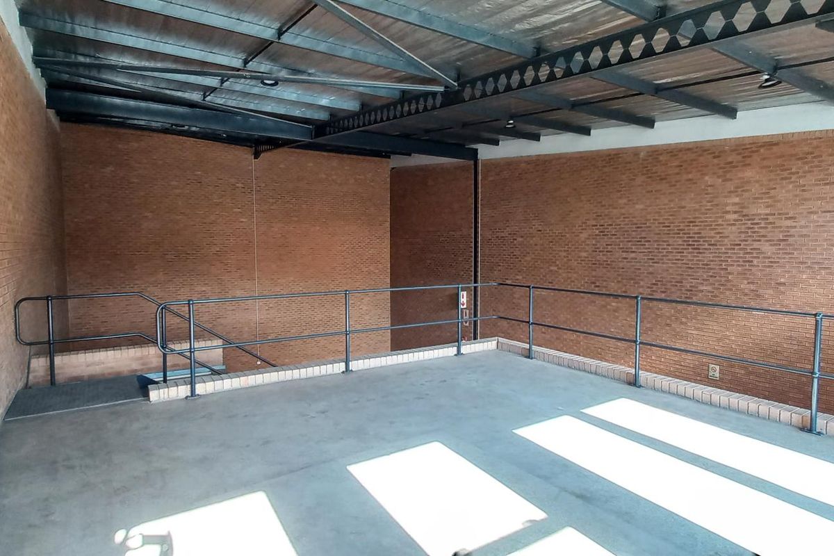 An open-plan industrial utility space featuring exposed steel roof trusses, face brick walls, and concrete flooring with a metal safety railing.