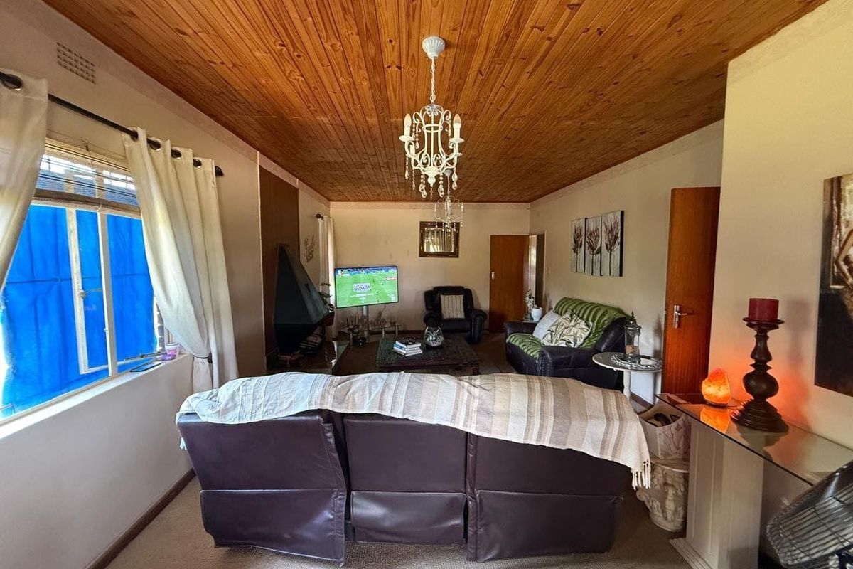 A living room featuring a timber-clad ceiling, a built-in corner fireplace, and carpeted flooring, providing a cozy and traditional living space.