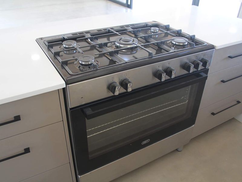 A modern kitchen island featuring a stainless steel gas stove and oven combination with sleek quartz countertops and contemporary cabinetry.