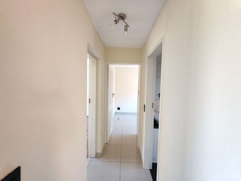 A clean, neutral hallway featuring tiled flooring and access to multiple rooms, providing a bright and functional transition space within the townhouse.