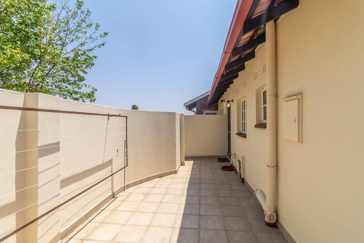 A private exterior courtyard area featuring tiled flooring, a wall-mounted washing line, and direct access to the side of the residence.