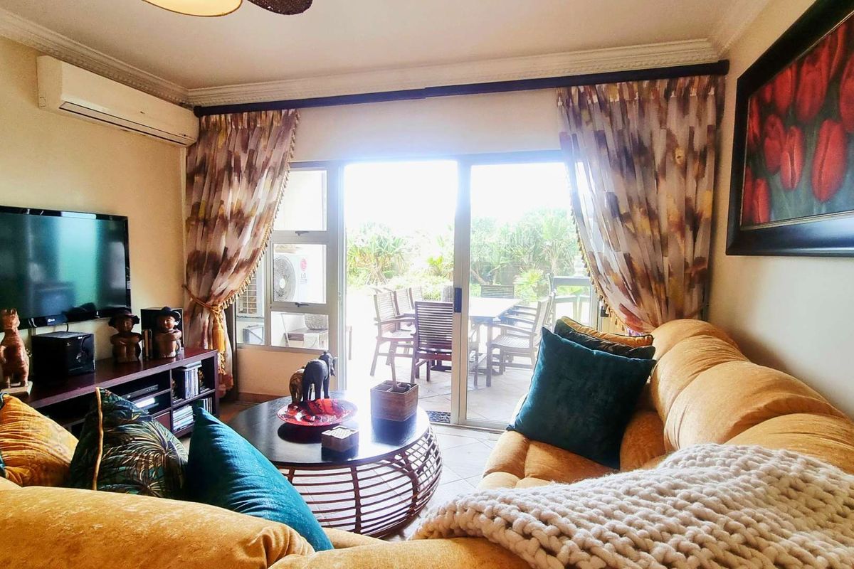 A comfortable living room featuring tiled flooring, cornice detailing, and a split-system air conditioner, with direct access to an outdoor patio area.