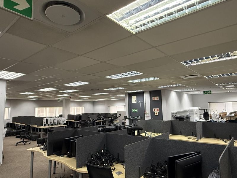Open-plan office space featuring suspended ceilings, recessed lighting, carpeted floors, and multiple built-in workstation partitions.