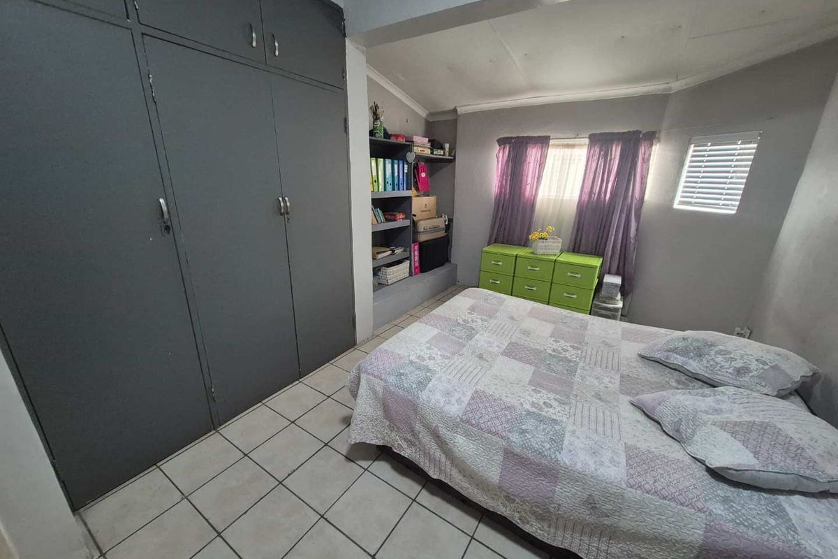 A bedroom featuring built-in floor-to-ceiling cupboards, tiled flooring, and integrated shelving units, providing functional storage space.
