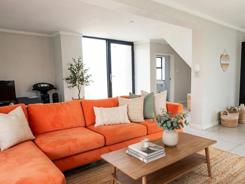 Spacious open-plan living area featuring neutral tiled flooring, recessed lighting, and seamless flow to the kitchen and outdoor access via sliding glass doors.
