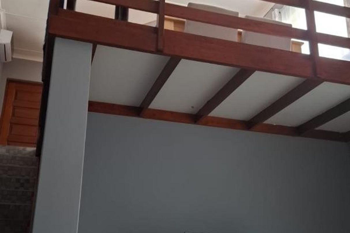 Living area featuring a mezzanine level with a timber balustrade, high ceilings, and tiled flooring.