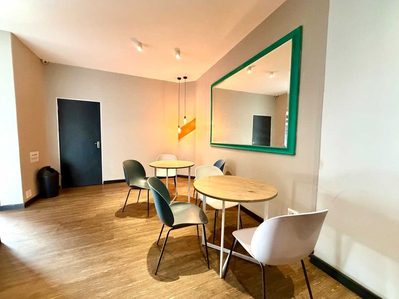 A modern living area featuring laminate flooring, recessed ceiling lights, and pendant lighting, creating a bright and functional space.