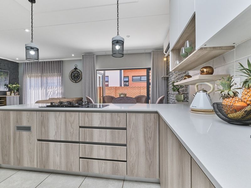 Modern open-plan kitchen featuring a central island with gas hob, stone countertops, and contemporary cabinetry, seamlessly flowing into the living and dining areas.
