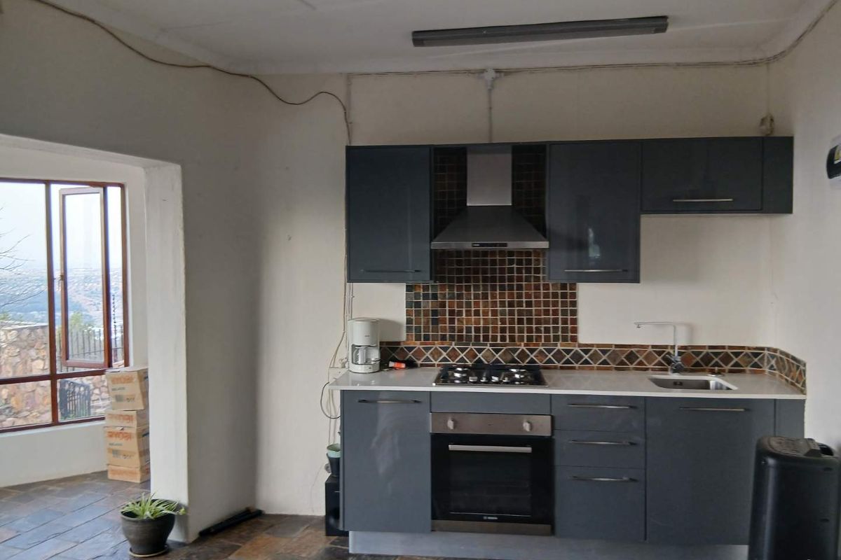 Compact kitchen featuring dark grey cabinetry, gas hob, built-in oven, mosaic tile backsplash, and slate flooring, with direct access to an outdoor area.