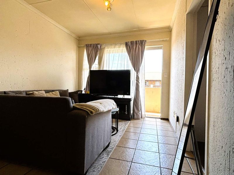 A living room featuring tiled flooring and a sliding door providing access to an outdoor area.