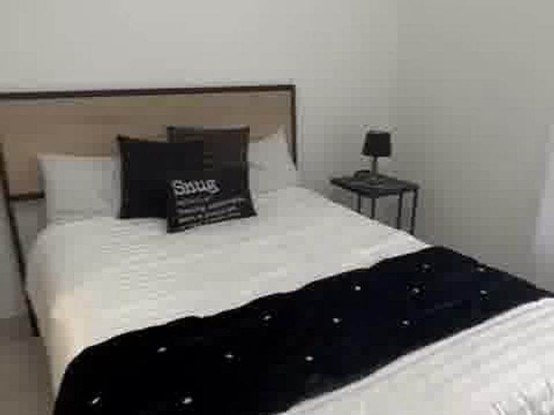 A simple bedroom featuring neutral walls and tiled flooring, providing a clean and functional space.
