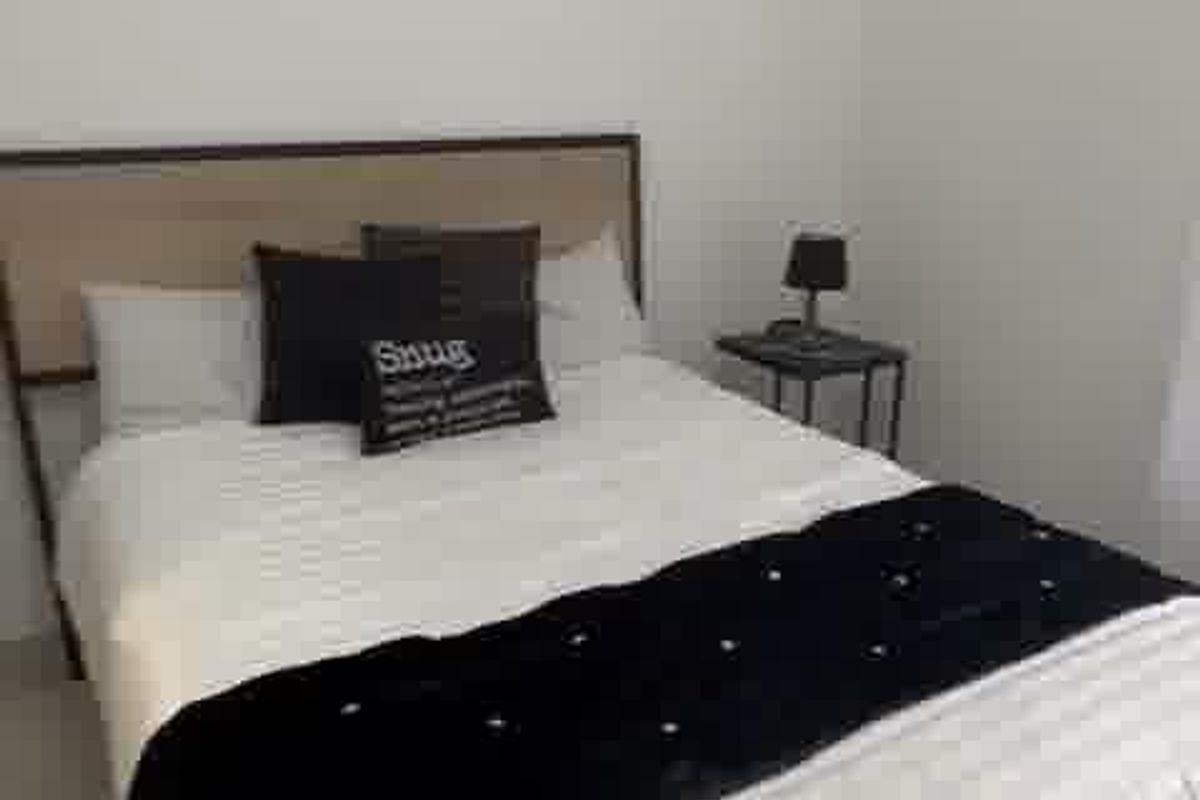 A simple bedroom featuring neutral walls and tiled flooring, providing a clean and functional space.