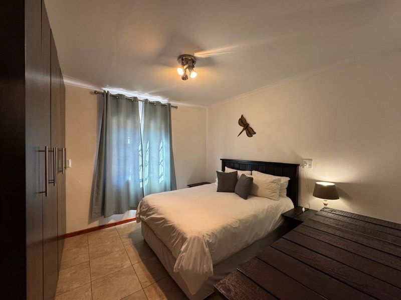 A functional bedroom featuring tiled flooring and built-in cupboards, providing essential storage and a neutral layout.