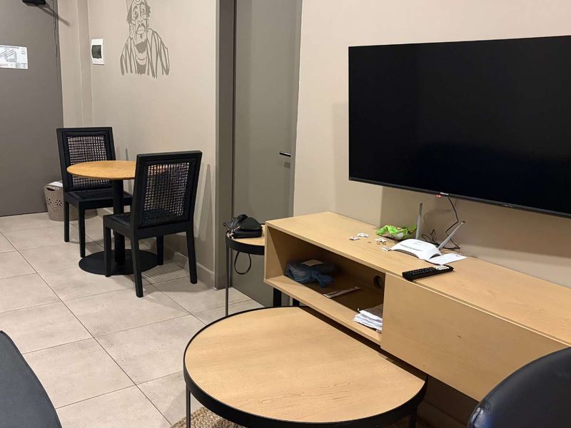 A functional living area featuring tiled flooring and neutral wall tones, providing a versatile space for relaxation and dining.