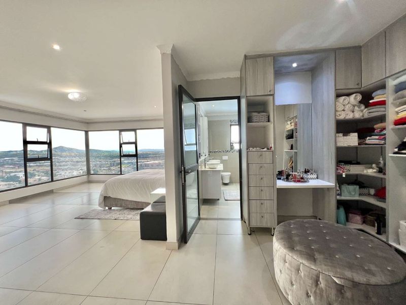 Spacious bedroom featuring large windows with panoramic views, integrated built-in cupboards with a vanity area, and direct access to an en-suite bathroom.