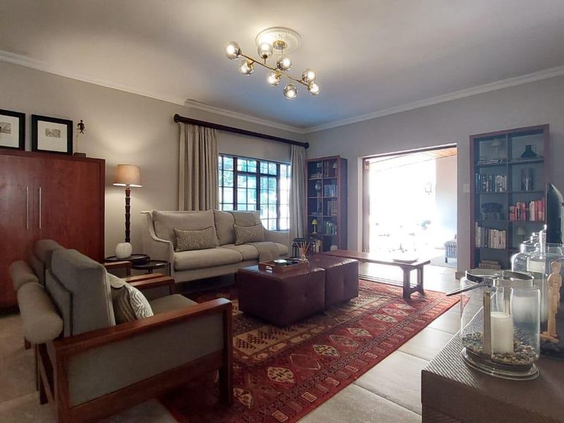 Spacious living room featuring tiled flooring, a modern chandelier, and direct access to an outdoor patio area through sliding glass doors.