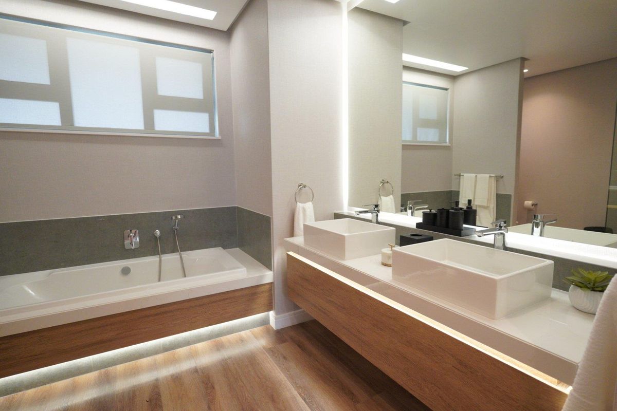 Modern bathroom featuring a floating double vanity with vessel sinks, integrated LED lighting, and a built-in bathtub with wood-look cabinetry.