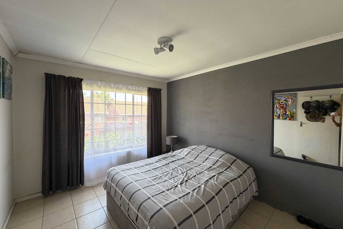 A bedroom featuring tiled flooring, a large window with natural light, and a dark accent wall.