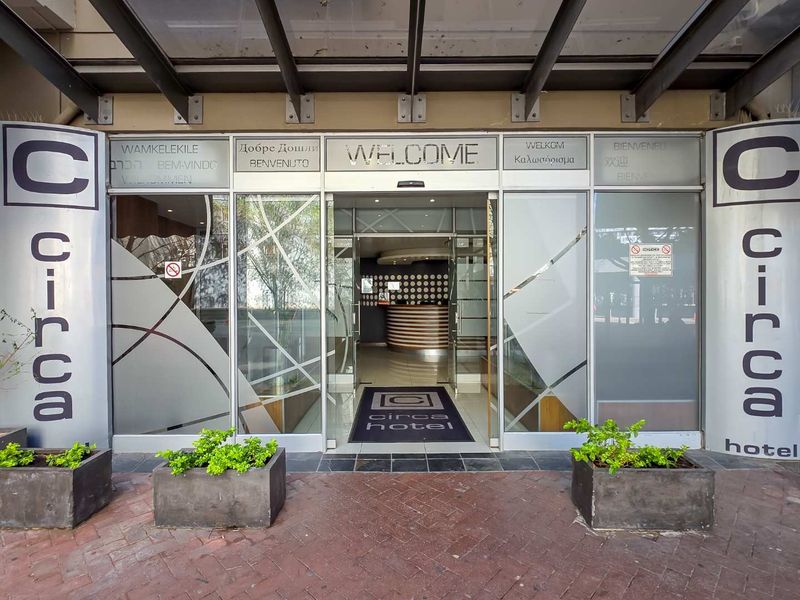 The main entrance to the Circa Hotel featuring glass sliding doors, a protective metal canopy, and professional signage.
