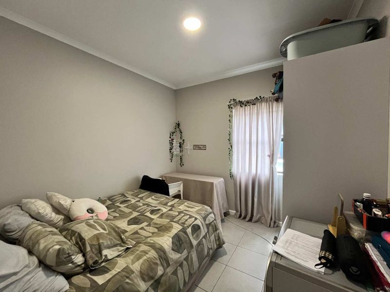 A standard bedroom featuring neutral wall paint, tiled flooring, and decorative cove cornicing, providing a functional and well-lit living space.