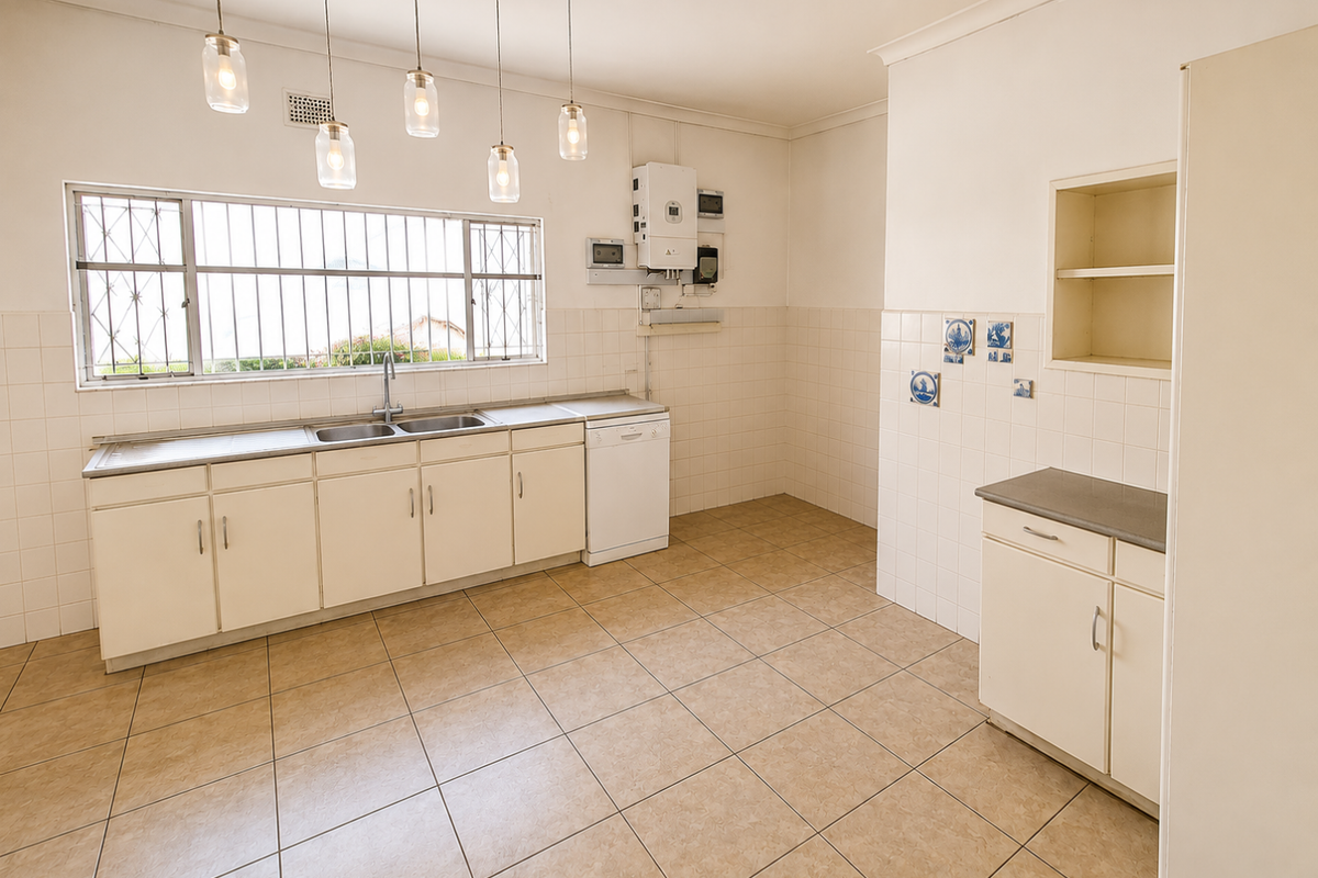 A spacious, functional kitchen featuring tiled flooring, ample built-in cabinetry, a double basin sink, and a wall-mounted gas geyser.