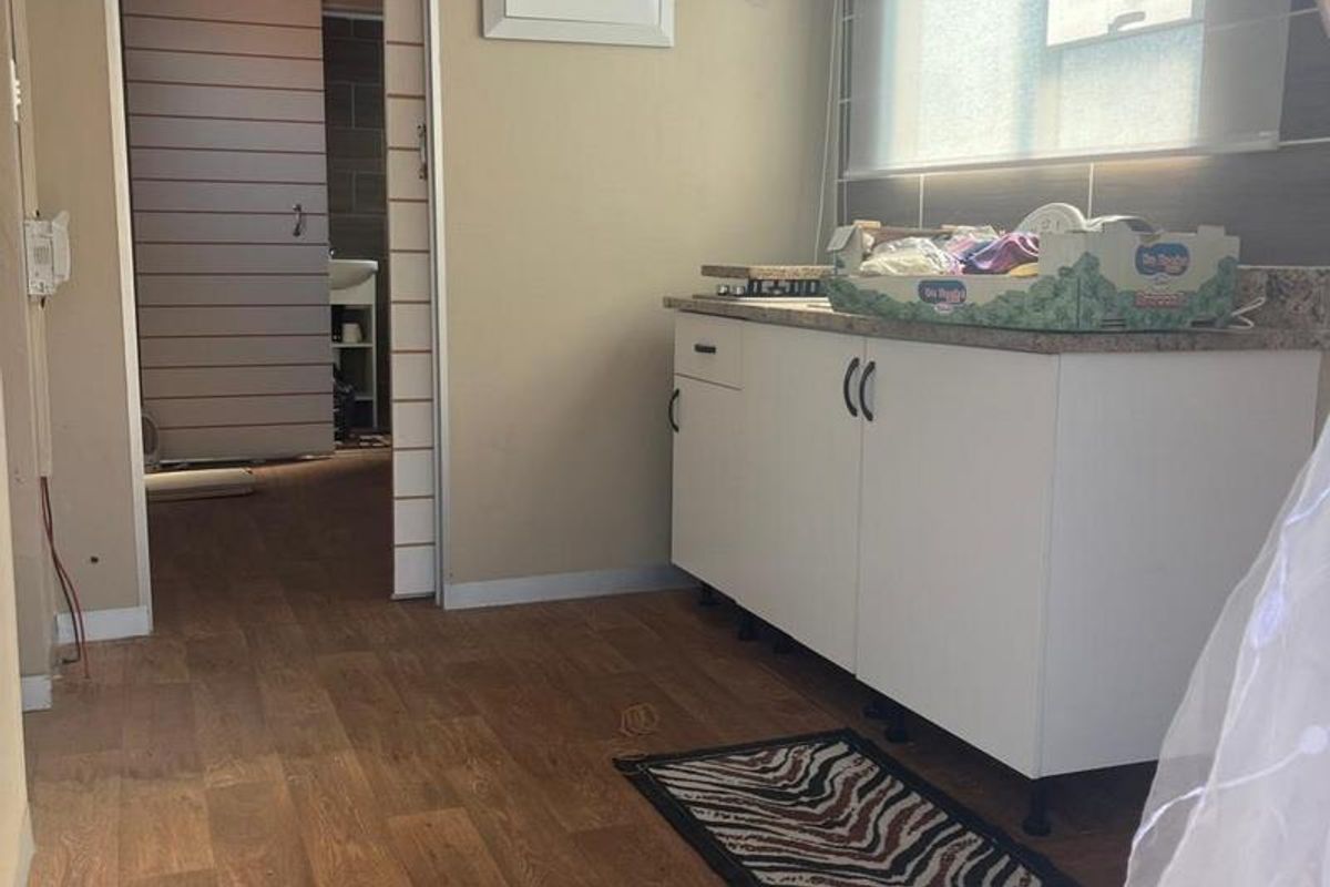 A functional kitchen area featuring built-in cabinetry, laminate countertops, and a window, with direct access to an adjacent bathroom.