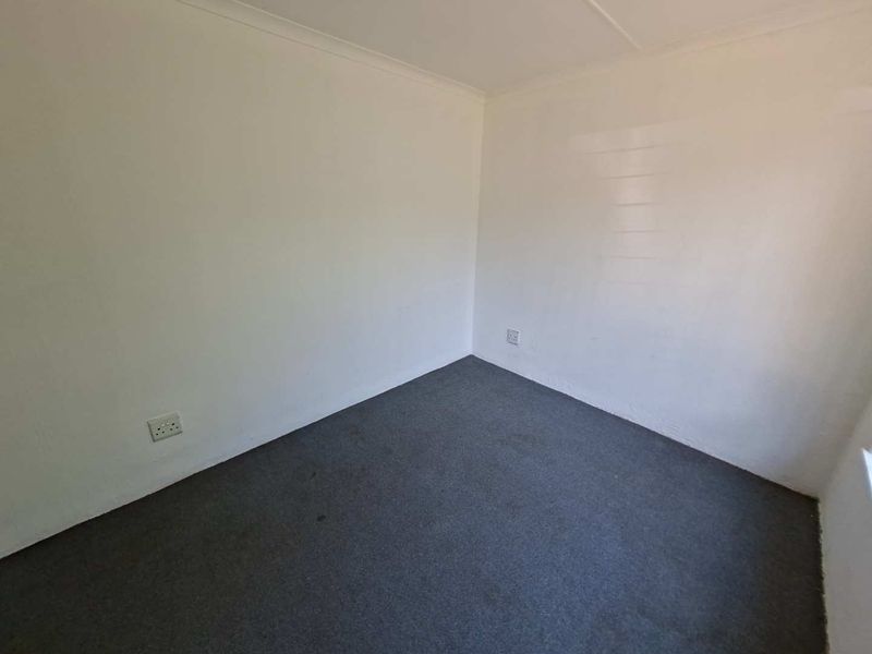 A clean, empty bedroom featuring neutral white walls, carpeted flooring, and coved ceiling detailing, providing a versatile blank canvas for personalization.