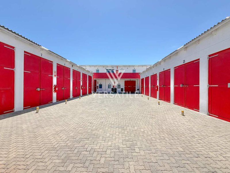 A well-maintained industrial complex featuring multiple storage units with red roller shutter doors and a paved central courtyard.