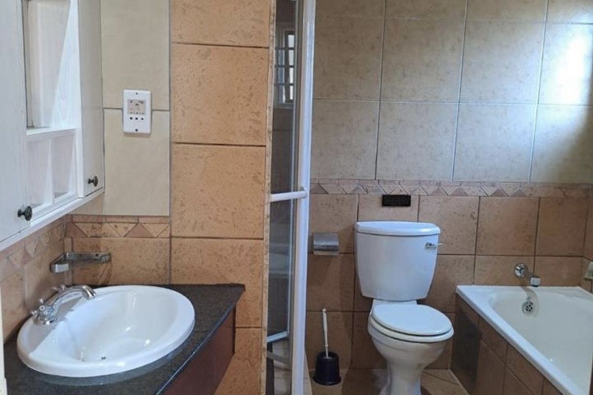 A functional bathroom featuring a vanity with basin, a separate shower enclosure, a toilet, and a bathtub with tiled finishes throughout.