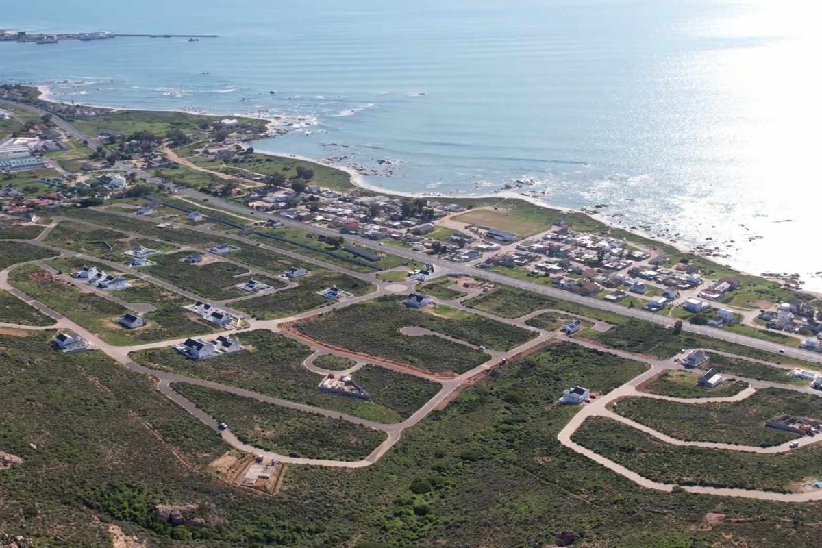 Aerial view of a coastal residential estate development featuring paved roads, established plots, and proximity to the ocean.