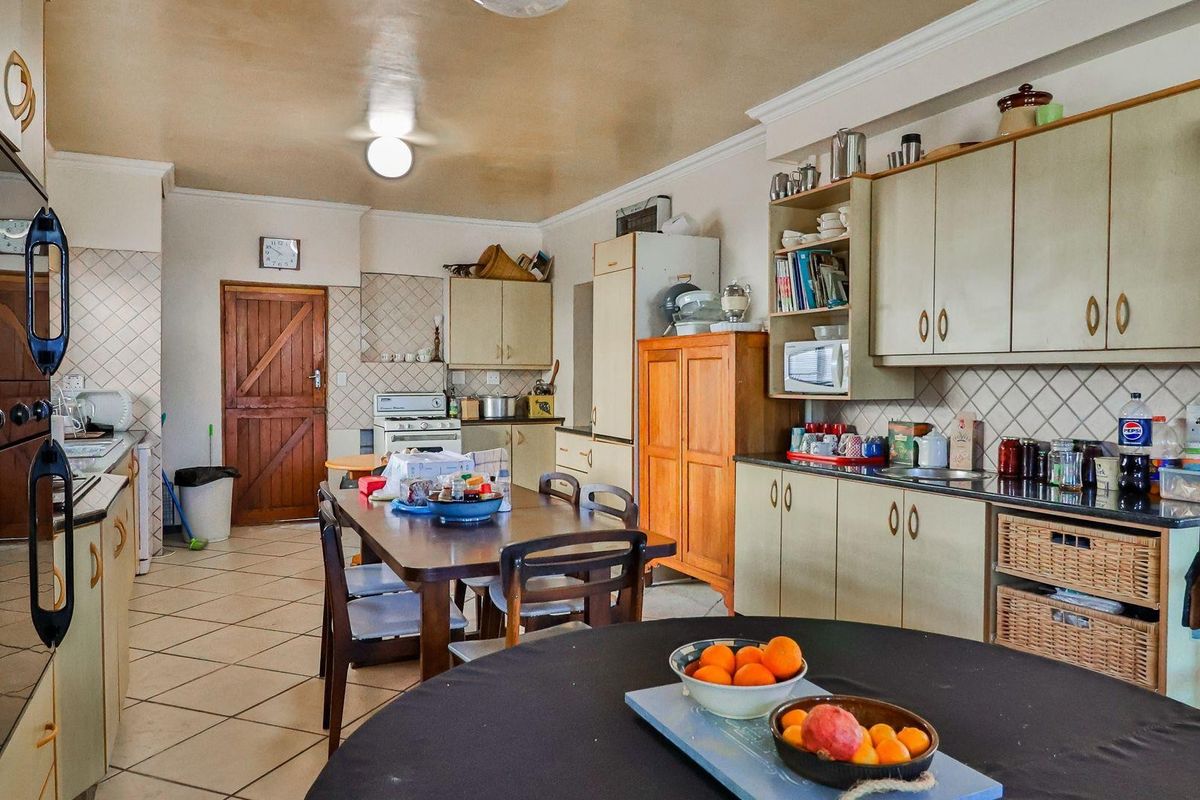 A spacious kitchen featuring built-in cabinetry, tiled flooring, and a functional layout with integrated oven and hob, offering potential for modernization.