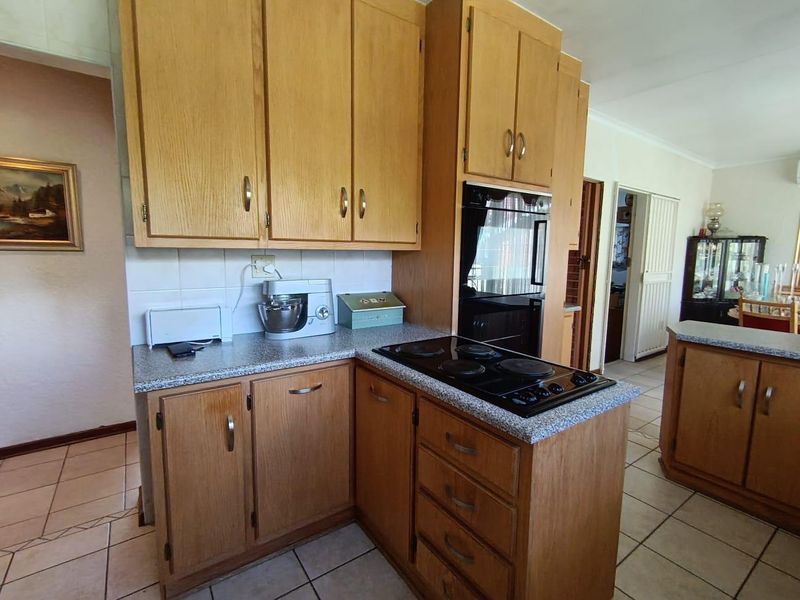 A functional kitchen featuring wood-tone cabinetry, laminate countertops, a built-in oven, and an electric cooktop with ceramic tile flooring.