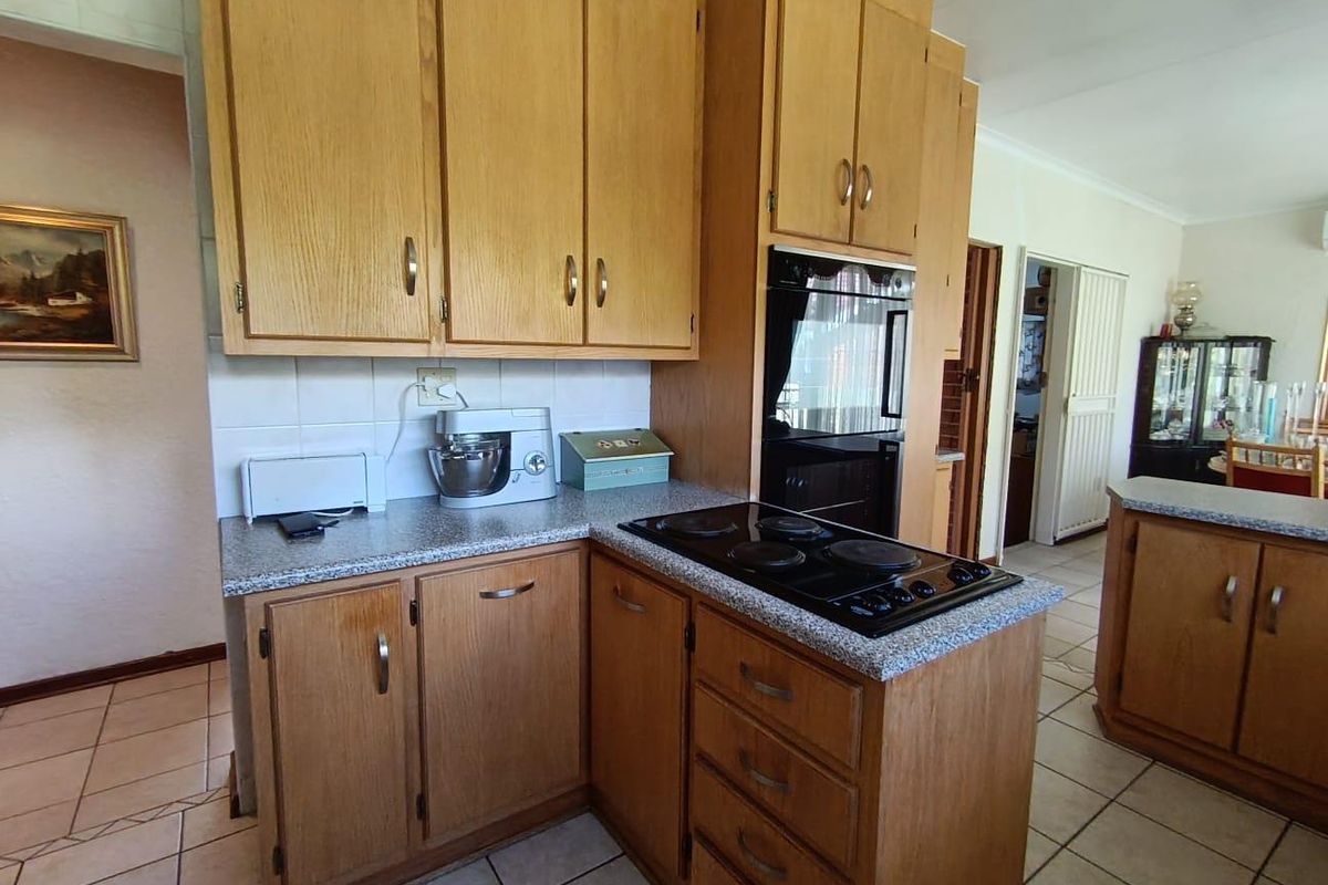 A functional kitchen featuring wood-tone cabinetry, laminate countertops, a built-in oven, and an electric cooktop with ceramic tile flooring.