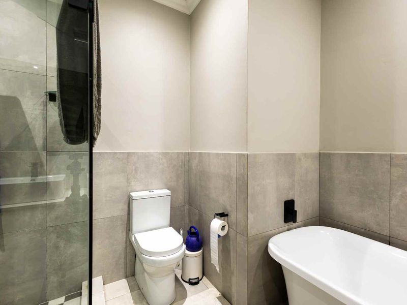 Modern bathroom featuring a freestanding bathtub, a glass-enclosed shower, and contemporary grey tiling throughout.