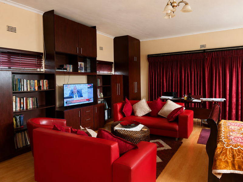 A living room featuring extensive built-in dark wood cabinetry and shelving, laminate flooring, and large window treatments.