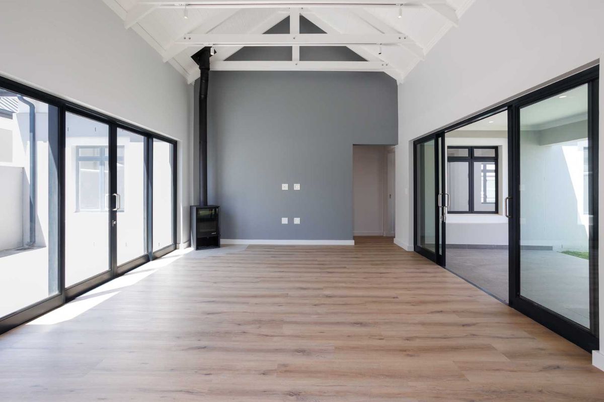 Spacious living area featuring high vaulted ceilings with exposed trusses, wood-burning fireplace, and large sliding glass doors providing abundant natural light.