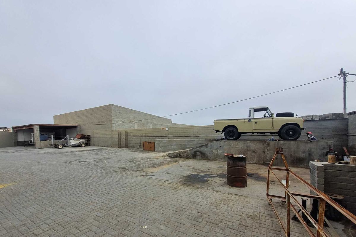 Industrial yard area featuring paved ground, a concrete loading ramp, and perimeter masonry walling suitable for commercial or storage use.