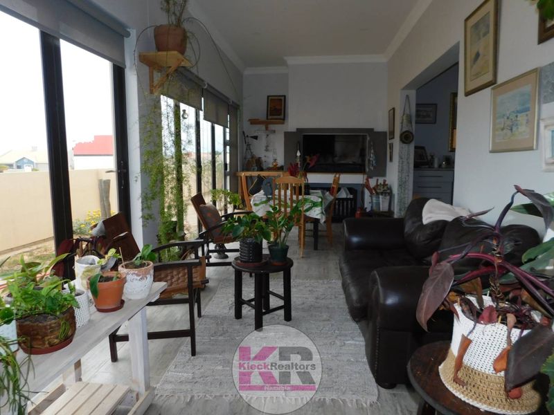 A bright living area featuring large sliding glass doors, tiled flooring, and a built-in fireplace, offering a comfortable and well-lit space.