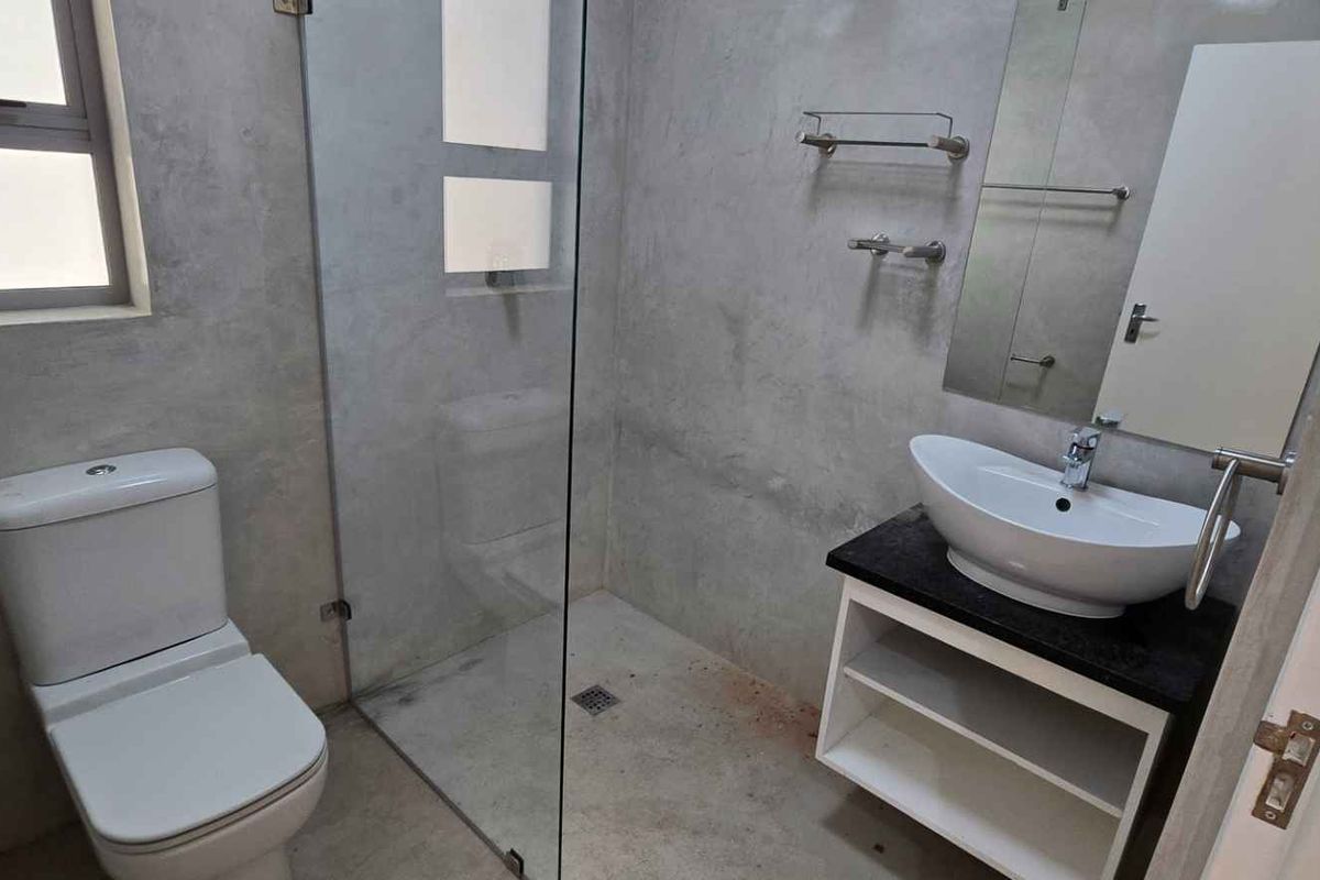 Modern bathroom featuring a walk-in glass shower, contemporary vanity with vessel sink, and polished concrete-style wall finishes.
