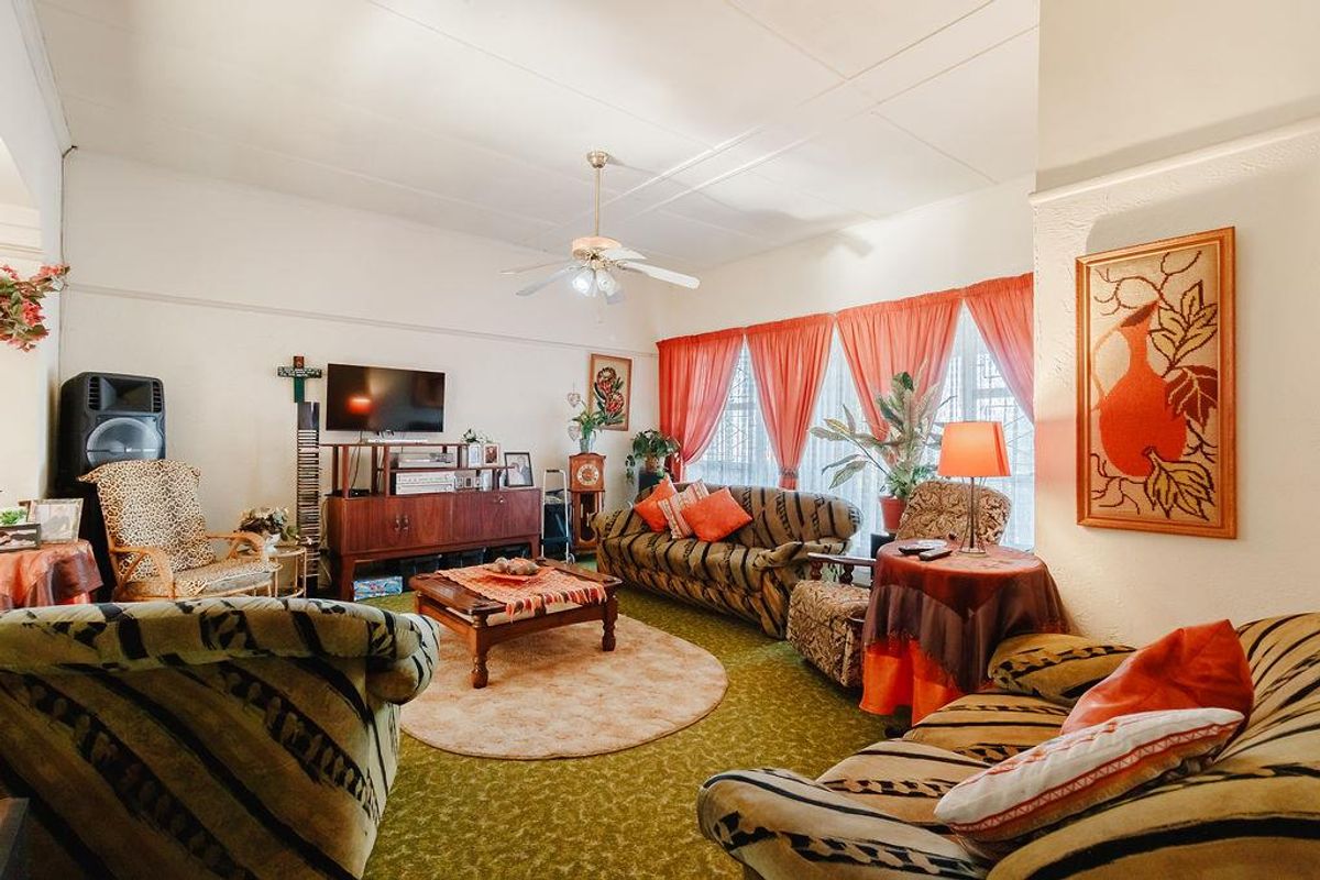 A spacious living room featuring a ceiling fan and coved ceilings, offering a comfortable area for relaxation and family gatherings.
