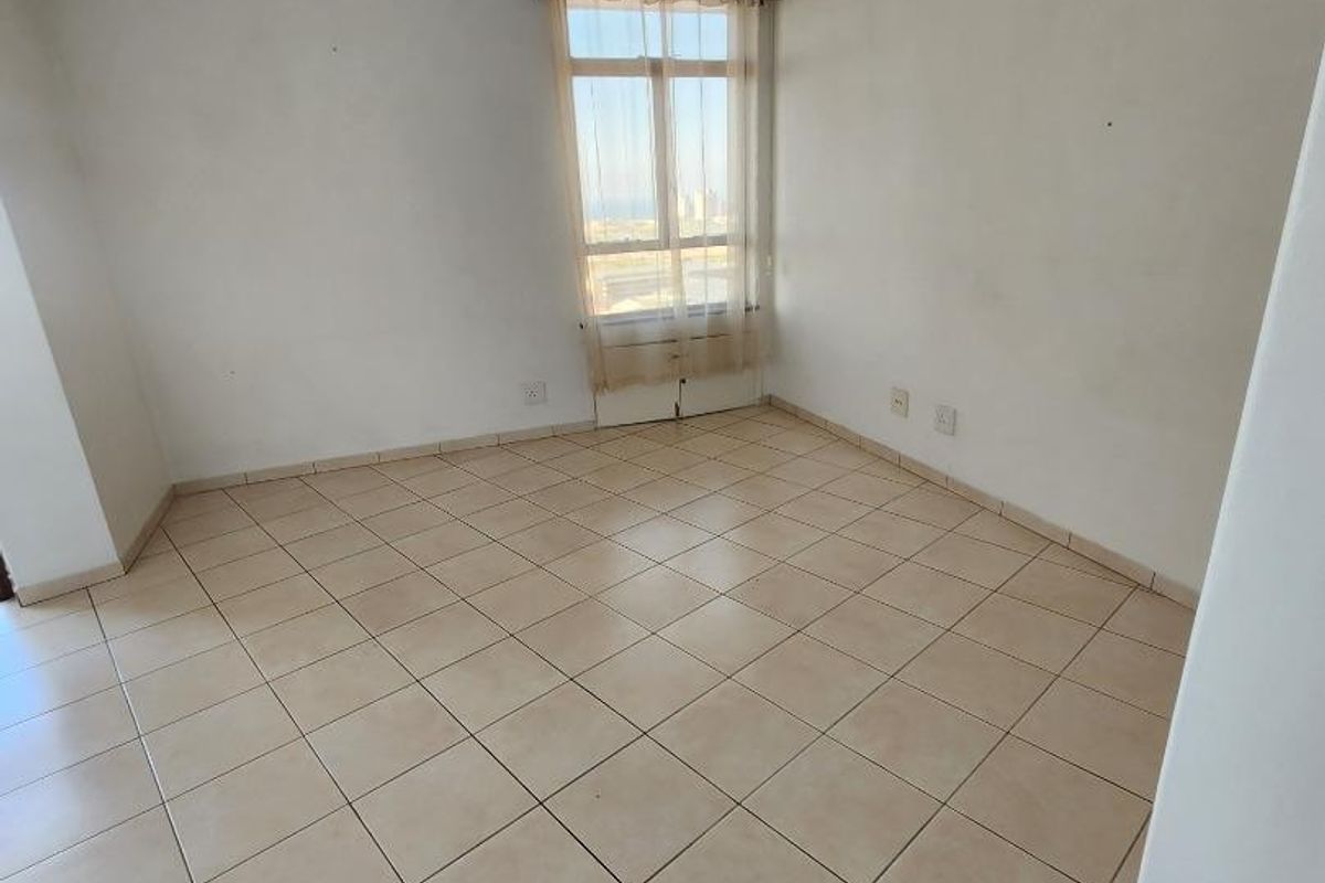 A vacant bedroom featuring neutral ceramic floor tiles, white walls, and a window with natural light, offering a blank canvas for personalization.