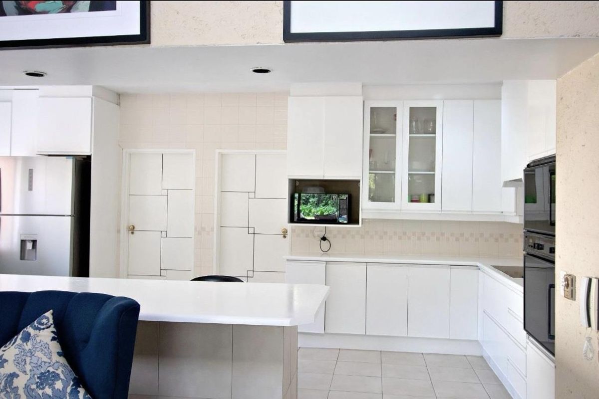 Modern kitchen featuring white cabinetry, integrated oven, built-in microwave, and a central island with a stone countertop.