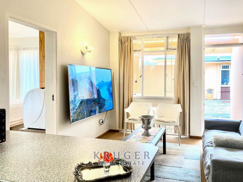 Open-plan living area featuring a granite kitchen counter, neutral walls, and direct access to an outdoor patio area through a sliding door.