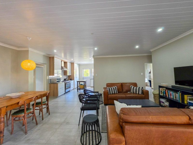 Spacious open-plan living area featuring a modern kitchen with built-in cabinetry, gas stove, and tiled flooring, seamlessly flowing into the dining and lounge space.