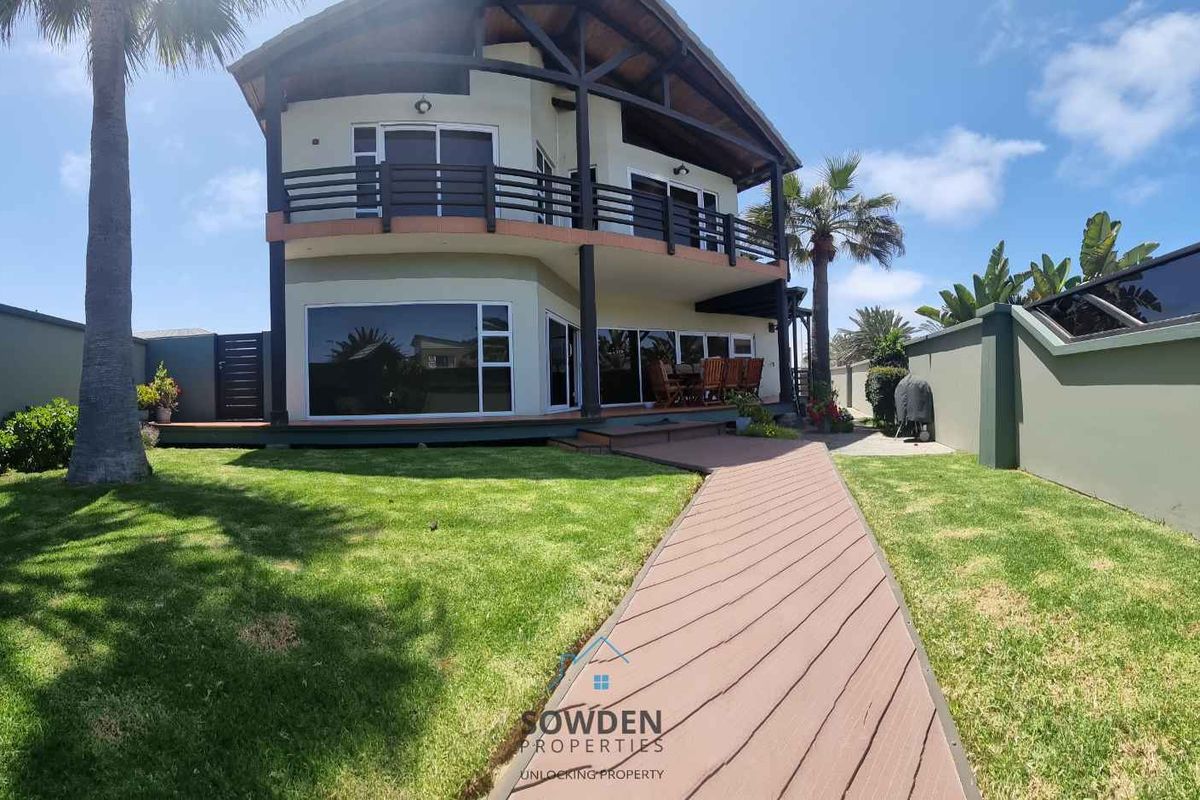 A well-maintained double-story house featuring a rear garden, timber decking, and a paved walkway leading to the main structure.