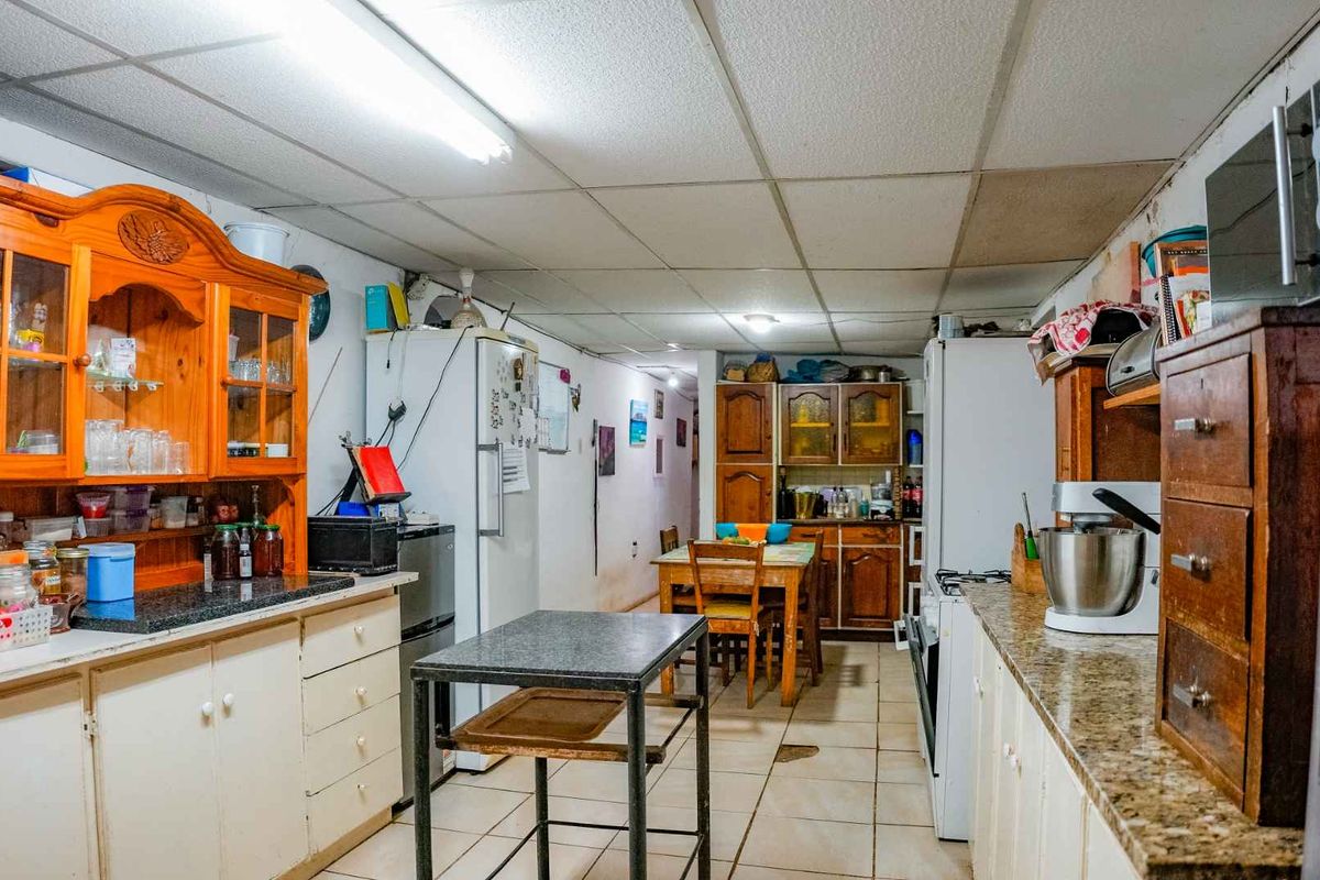 A dated kitchen featuring traditional wooden cabinetry, granite-style countertops, and a drop ceiling, offering a functional layout with significant potential for modernization.
