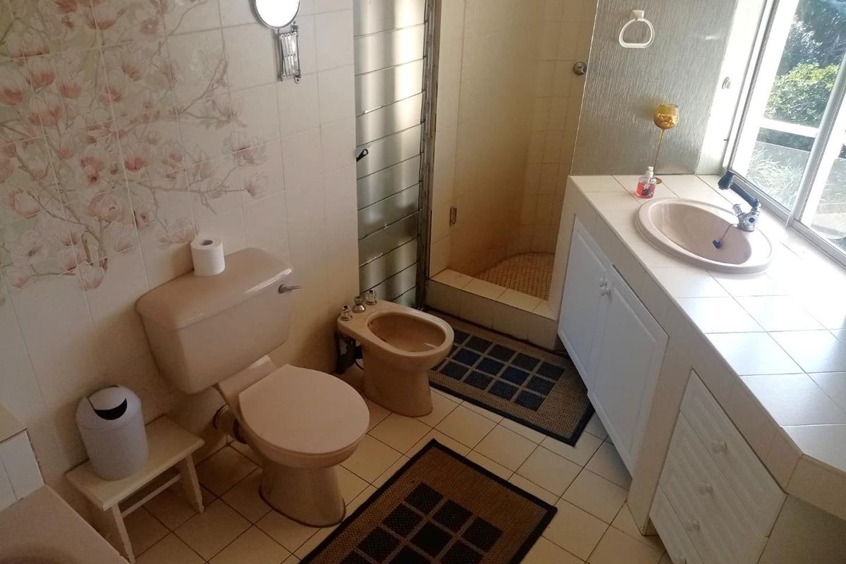 A dated bathroom featuring a built-in vanity, shower enclosure, bidet, and toilet with original tiled finishes.