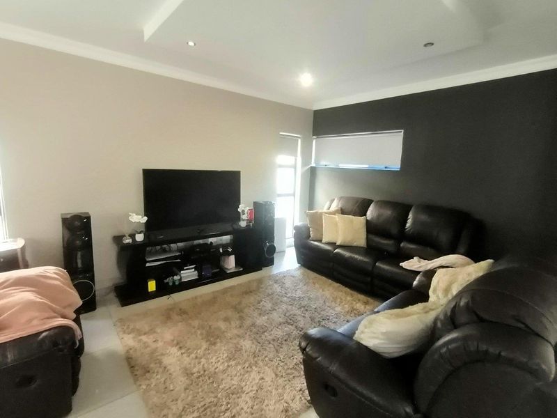 A comfortable living room featuring a recessed ceiling with downlights and a modern roller blind, providing a clean and functional space.